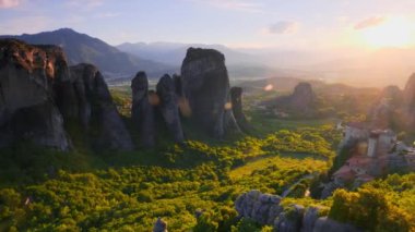 Yunanistan 'ın ünlü Yunan turizm beldesi Meteora' da, Rousanou manastırı ve St. Nicholas Anapavsa Manastırı 'nın üzerinde gün batımı güneş ışınları ve merceklerle parlıyor. Yatay kamera tavası