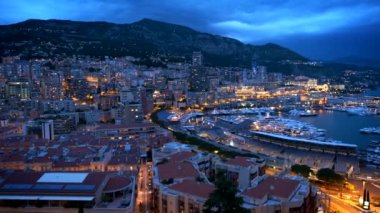 Monaco Monte Carlo limanı ve şehir silueti manzarası. Monaco Limanı gece görüşü ve hızlı hareket eden bulutlar. Yatay kamera tavası