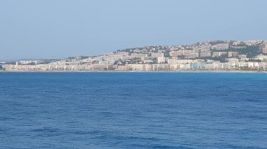 Nice, Fransa 'daki Akdeniz kıyılarının manzaralı manzarası. Akdeniz dalgaları kıyıya vuruyor, insanlar sahilde dinleniyor. Güzel, France. Kamera yatay tavası