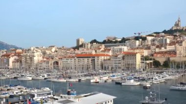 Marsilya Eski Limanı (Vieux-Port de Marseille) yatları ve Notre-Dame de la Garde Bazilikası ile. Marsilya, Fransa. Kamera yansı hareketi