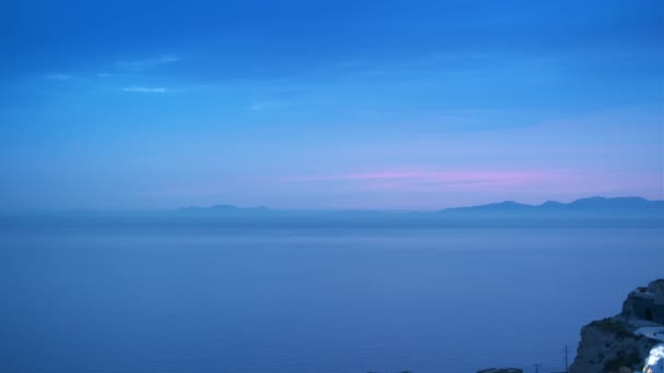 ギリシャの夜にサントリーニ島の伝統的な白い家と風車を持つ有名なギリシャの象徴的なセルフィスポット観光地オイア村 横カメラ — ストック動画
