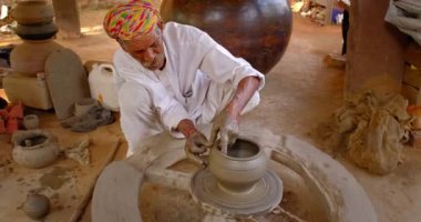 Çömlekçi çarkını fırlatan ve geleneksel seramik kap ve kil kaplarını şekillendiren usta bir çömlekçi: çömlek atölyesinde esrar, kavanoz. Shilpagram, Udaipur, Rajasthan, Hindistan 'dan el işi.