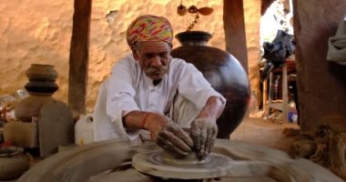Çömlekçi çarkını fırlatan ve geleneksel seramik kap ve kil kaplarını şekillendiren usta bir çömlekçi: çömlek atölyesinde esrar, kavanoz. Shilpagram, Udaipur, Rajasthan, Hindistan 'dan el işi.