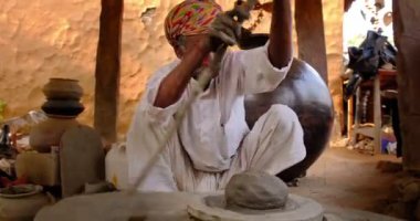 Çömlekçi çarkını fırlatan ve geleneksel seramik kap ve kil kaplarını şekillendiren usta bir çömlekçi: çömlek atölyesinde esrar, kavanoz. Shilpagram, Udaipur, Rajasthan, Hindistan 'dan el işi.