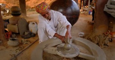 Çömlekçi çarkını fırlatan ve geleneksel seramik kap ve kil kaplarını şekillendiren usta bir çömlekçi: çömlek atölyesinde esrar, kavanoz. Shilpagram, Udaipur, Rajasthan, Hindistan 'dan el işi.