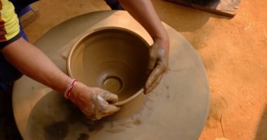 Çömlekçinin becerikli ıslak elleri çömlekçi çarkındaki killeri şekillendiriyor ve vazo yontuyor. Geleneksel el yapımı Hint kasesi, kavanoz, esrar, sürahi üretiyor. Shilpagram, Udaipur, Rajasthan, Hindistan