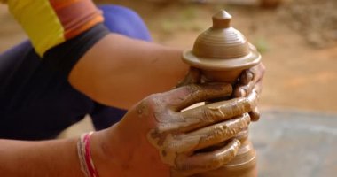 Çömlekçinin becerikli ıslak elleri çömlekçi çarkındaki killeri şekillendiriyor ve vazo yontuyor. Geleneksel el yapımı Hint kasesi, kavanoz, esrar, sürahi üretiyor. Shilpagram, Udaipur, Rajasthan, Hindistan
