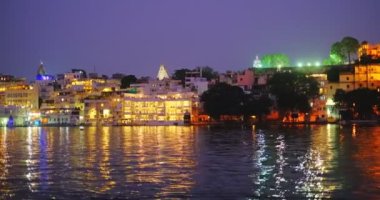 Ünlü lüks Udaipur Şehir Sarayı, Lal ghat, Pichola Gölü kıyısında evler günbatımında su dalgalarıyla aydınlandı - Mewars 'ın Rajput mimarisi. Udaipur, Rajasthan, Hindistan. Yatay tava