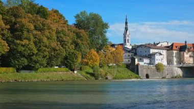 Meşhur turistik kent Bad Tolz 'da altın sonbahar. Isar nehrinin manzarası, ağaçlar, kasaba köprüsü, cennet gibi Bavyera evleri ve kilise. Bad Toelz, Bavyera, Almanya. Yatay kaydırma