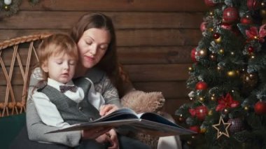 Anne ve tatlı çocuk Noel ağacının altında masal okuyorlar.