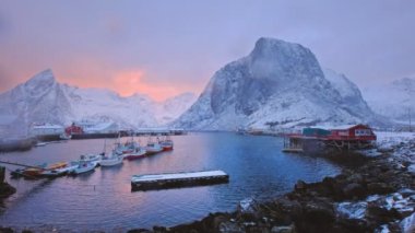 Norveç 'in Lofoten Adaları' ndaki Hamnoy balıkçı köyünde gemileriyle rıhtımda kışın gün doğumunda kırmızı rorbu evleri