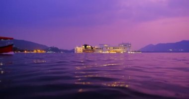Udaipur Gölü Sarayı 'nın ünlü lüksü Jaguar Nivalar gün batımında Pichola Gölü' nde Rajput mimarisi Rajasthan 'ın Mewar Hanedanı' nın hükümdarları. Geçen bir turist teknesiyle. Udaipur, Rajasthan, Hindistan