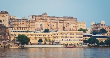 Günbatımında Pichola Gölü 'nden Udaipur Şehir Sarayı manzaralı bir turist teknesi geçiyor. Jag Niwas Rajput mimarisinin bir örneğidir. Rajasthan, Hindistan 'ın popüler turistik yeridir. İnanılmaz Hindistan mirası..