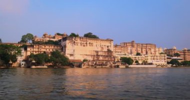 Pichola gölündeki hareket halindeki tekneden Udaipur Şehir Sarayı manzarası. Lüks beyaz saray Rajput mimarisi Rajasthan 'ın Mewar Hanedanı hükümdarları ve Hindistan' ın ünlü turist simgesidir. İnanılmaz Hindistan mirası.