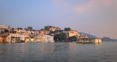 Pichola gölündeki hareket halindeki tekneden Udaipur Şehir Sarayı manzarası. Lüks saray Rajput mimarisi Rajasthan 'ın Mewar Hanedanı hükümdarları ve Hindistan' ın ünlü turist simgesidir. İnanılmaz Hindistan mirası..