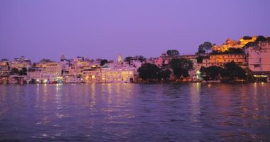 Ünlü lüks Udaipur Şehir Sarayı, Lal ghat, Pichola Gölü kıyısında evler günbatımında su dalgalarıyla aydınlandı - Mewars 'ın Rajput mimarisi. Udaipur, Rajasthan, Hindistan. Yatay tava