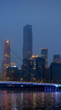 Guangzhou 'nun Zhujiang İnci Nehri üzerindeki Liede Köprüsü manzarası ve geceleri aydınlanan finansal bölgenin modern gökdelenleri. Guangzhou, Çin. Kamera tavası