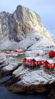 Norveç, Lofoten Adaları 'ndaki meşhur geleneksel balıkçı köyü Hamnoy' da kışın karlı kırmızı rorbu evleri