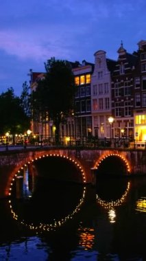 Akşam alacakaranlıkta Amsterdam 'ın kanal, köprü ve ortaçağ evleriyle gece manzarası aydınlandı. Amsterdam, Hollanda. Kamera tavası