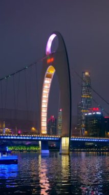 Guangzhou 'nun Zhujiang Nehri üzerindeki Liede Köprüsü manzarası ve finans bölgesinin modern gökdelenleri gece aydınlandı ve köprü altından geçen turist botu görülüyor. Guangzhou, Çin
