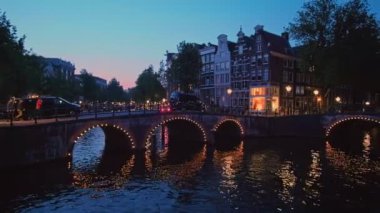 Akşam alacakaranlıkta Amsterdam 'ın kanal, köprü ve ortaçağ evleriyle gece manzarası aydınlandı. Amsterdam, Hollanda. Yatay kamera tavası