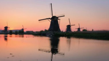 Hollanda 'nın ünlü turizm sahası Kinderdijk' te yel değirmenleriyle dolu kırsal bölgelerinde gün batımında dramatik bir gökyüzü ve kanalda ördekler