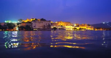 Gün batımında güzel Pichola Gölü kıyısındaki Udaipur Şehir Sarayı Rajput mimarisi Rajasthan 'ın Mewar Hanedanı hükümdarları. Su dalgaları şehir manzarasını yansıtır. Udaipur, Hindistan