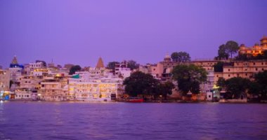 Ünlü lüks Udaipur Şehir Sarayı, Lal ghat, Pichola Gölü kıyısında evler günbatımında su dalgalarıyla aydınlandı - Mewars 'ın Rajput mimarisi. Udaipur, Rajasthan, Hindistan. Yatay tava