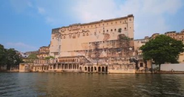 Pichola gölündeki hareket halindeki tekneden Udaipur Şehir Sarayı manzarası. Lüks saray Rajput mimarisi Rajasthan 'ın Mewar Hanedanı hükümdarları ve Hindistan' ın ünlü turist simgesidir. İnanılmaz Hindistan mirası..