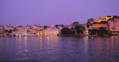 Ünlü lüks Udaipur Şehir Sarayı, Lal ghat, Pichola Gölü kıyısında evler günbatımında su dalgalarıyla aydınlandı - Mewars 'ın Rajput mimarisi. Udaipur, Rajasthan, Hindistan. Yatay tava