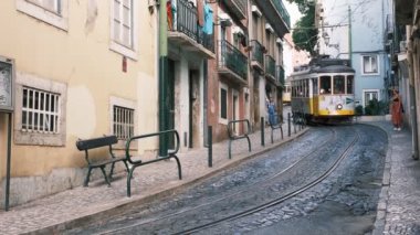 Lizbon, Portekiz - 26 Ağustos 2022: Lizbon, Portekiz 'in Alfama ilçesinin dar sokaklarında ünlü klasik sarı tramvay - Lizbon' un sembolü, ünlü popüler seyahat ve turizm merkezi