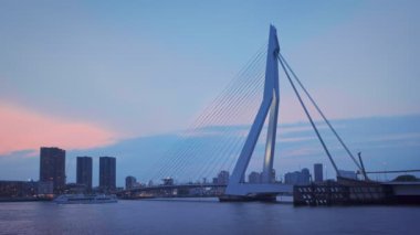 Rotterdam, Hollanda - 24 Mayıs 2018: Erasmus Köprüsü 'nün (Erasmusbrug) altından geçen yolcu gemisi ve Rotterdam silueti alacakaranlıkta aydınlandı. Rotterdam, Hollanda