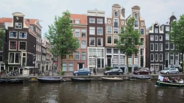 Amsterdam, Hollanda - 22 Mayıs 2018: Amsterdam pitoresk şehir manzarası - kanal boyunca geçen turist tekneleri, köprüsü ve eski evleri ile sokak ve kanal