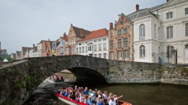 Bruges, Belçika - 29 Mayıs 2018: Bruges Kanalı 'nda eski köprünün altından geçen eski ortaçağ mimari evleri olan turist tekneleri. Brugge, Belçika