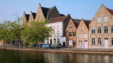 Bruges, Belçika - 28 Mayıs 2018: Tipik Belçika şehir manzarası Avrupa turizm konsepti - kanal ve eski evler gün batımında kadınlar kanal boyunca koşu yaparken. Bruges (Brugge), Belçika