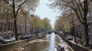 Amsterdam, Hollanda - 7 Mayıs 2017: Amsterdam Manzarası - eski köprü evlerinin altından geçen turist botu kanalı. Amsterdam, Hollanda