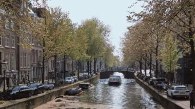 Amsterdam, Hollanda - 7 Mayıs 2017: Amsterdam manzaralı - turist teknesi, köprüsü ve eski evleri olan kanal. Amsterdam, Hollanda