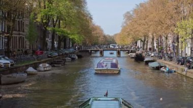 Amsterdam, Hollanda - 7 Mayıs 2017: Amsterdam Manzarası - eski köprü evlerinin altından geçen turist botu kanalı. Amsterdam, Hollanda