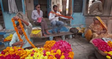 Pushkar, Hindistan - 7 Kasım 2019 - Hintli çiçekçi çiçek satıcısı çiçek pazarındaki Pushkar sokaklarında dini amaçlar için çiçek satıyor. Pushkar, Rajasthan, Hindistan