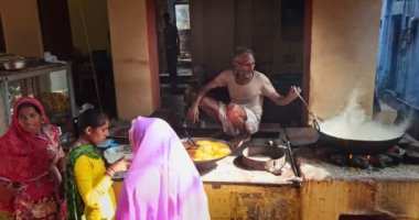 Pushkar, Hindistan - 7 Kasım 2019: Hindistan 'ın Rajasthan şehrinde sokak yemeklerinden alışveriş yapan kadın tatlı püre ve haham tatlısı, yoğunlaştırılmış süt tabanlı yemek pişiriyor.