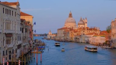 Venedik, İtalya - 19 Temmuz 2019: günbatımında Ponte dell 'Accademia Köprüsü' nden Santa Maria della Salute kilisesine giden gondol ve vaporetto tekneli Venedik Büyük Kanalı manzarası. Kamera tavası