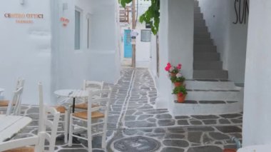 NAOUSA, GREECE - 27 Mayıs 2019: Yunanistan 'ın Paros Adası' nın ünlü turistik beldesi Paros 'ta, Naousa kasabasının çiçek açan begonvil çiçekli, badanalı evleri ile pitoresk caddede sabit bir kamerayla yürümek