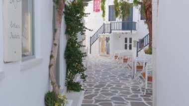 NAOUSA, GREECE - 27 Mayıs 2019: Yunanistan 'ın Paros Adası' nın ünlü turistik beldesi Paros 'ta, Naousa kasabasının çiçek açan begonvil çiçekli, badanalı evleri ile pitoresk caddede sabit bir kamerayla yürümek
