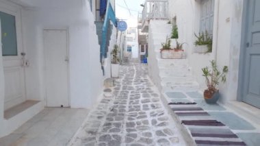 NAOUSA, GREECE - 27 Mayıs 2019: Yunanistan 'ın Paros Adası' nın ünlü turistik beldesi Paros 'ta, Naousa kasabasının çiçek açan begonvil çiçekli, badanalı evleri ile pitoresk caddede sabit bir kamerayla yürümek