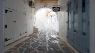 NAOUSA, GREECE - 27 Mayıs 2019: Yunanistan 'ın Paros Adası' nın ünlü turistik beldesi Paros 'ta, Naousa kasabasının çiçek açan begonvil çiçekli, badanalı evleri ile pitoresk caddede sabit bir kamerayla yürümek