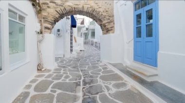 NAOUSA, GREECE - 27 Mayıs 2019: Yunanistan 'ın Paros Adası' nın ünlü turistik beldesi Paros 'ta, Naousa kasabasının çiçek açan begonvil çiçekli, badanalı evleri ile pitoresk caddede sabit bir kamerayla yürümek