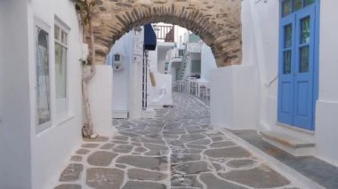 NAOUSA, GREECE - 27 Mayıs 2019: Yunanistan 'ın Paros Adası' nın ünlü turistik beldesi Paros 'ta, Naousa kasabasının çiçek açan begonvil çiçekli, badanalı evleri ile pitoresk caddede sabit bir kamerayla yürümek