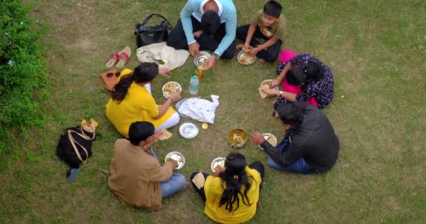 Kumbhalgarh インド ナイジェリア 2019 伝統的なインドの昼食を持っている未確認のインドの家族の概観 草の上に座って 食欲料理 カレーマサラバリヤーニを食べる — ストック動画