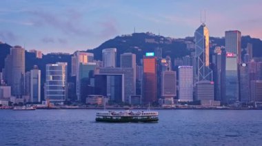 HONG KONG, ÇİN - 1 Mayıs 2018: Hong Kong gökdelenleri şehir merkezi gökdelenleri Victoria Limanı üzerinde akşamları turist botu ve feribot ile aydınlatılır. Kamera tavası