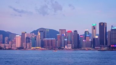 HONG KONG, ÇİN - 1 Mayıs 2018: Hong Kong gökdelenleri şehir merkezi gökdelenleri Victoria Limanı üzerinde akşamları turist botu ve feribot ile aydınlatılır. Hong Kong, Çin. Kamera tavası